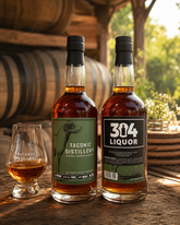 Lifestyle shot of Taconic Distillery bourbon bottles with a barrel background.